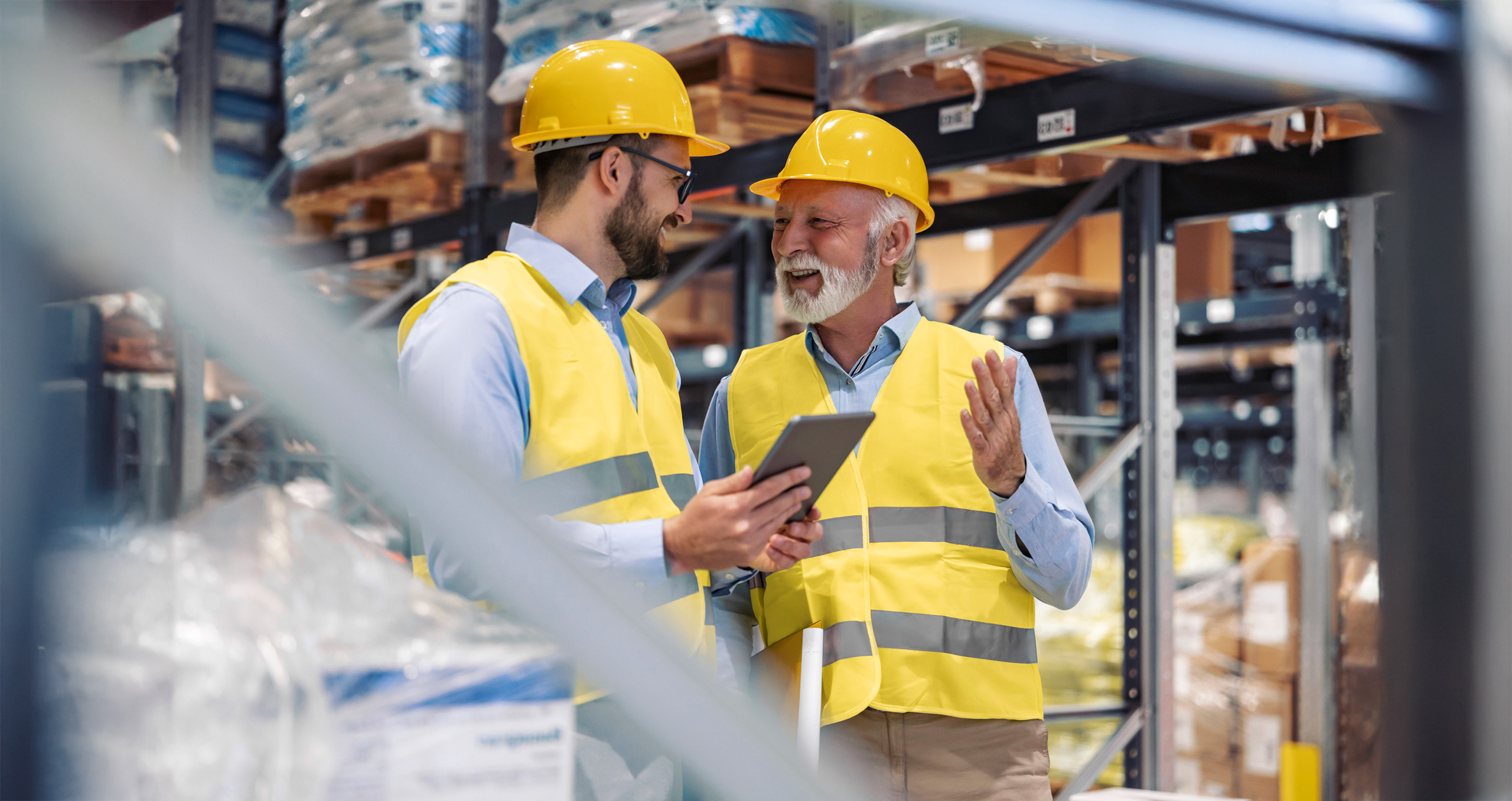 Zwei Mitarbeitende mit Schutzhelm besprechen Produktionsprozesse in moderner Fertigungshalle